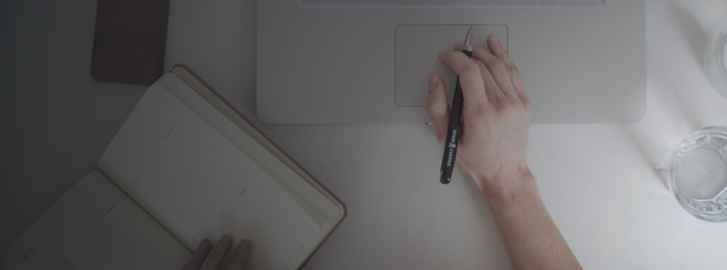 Lawyer at desk with one hand on appointment book, the other hand touching laptop to manage Clio SMS messages