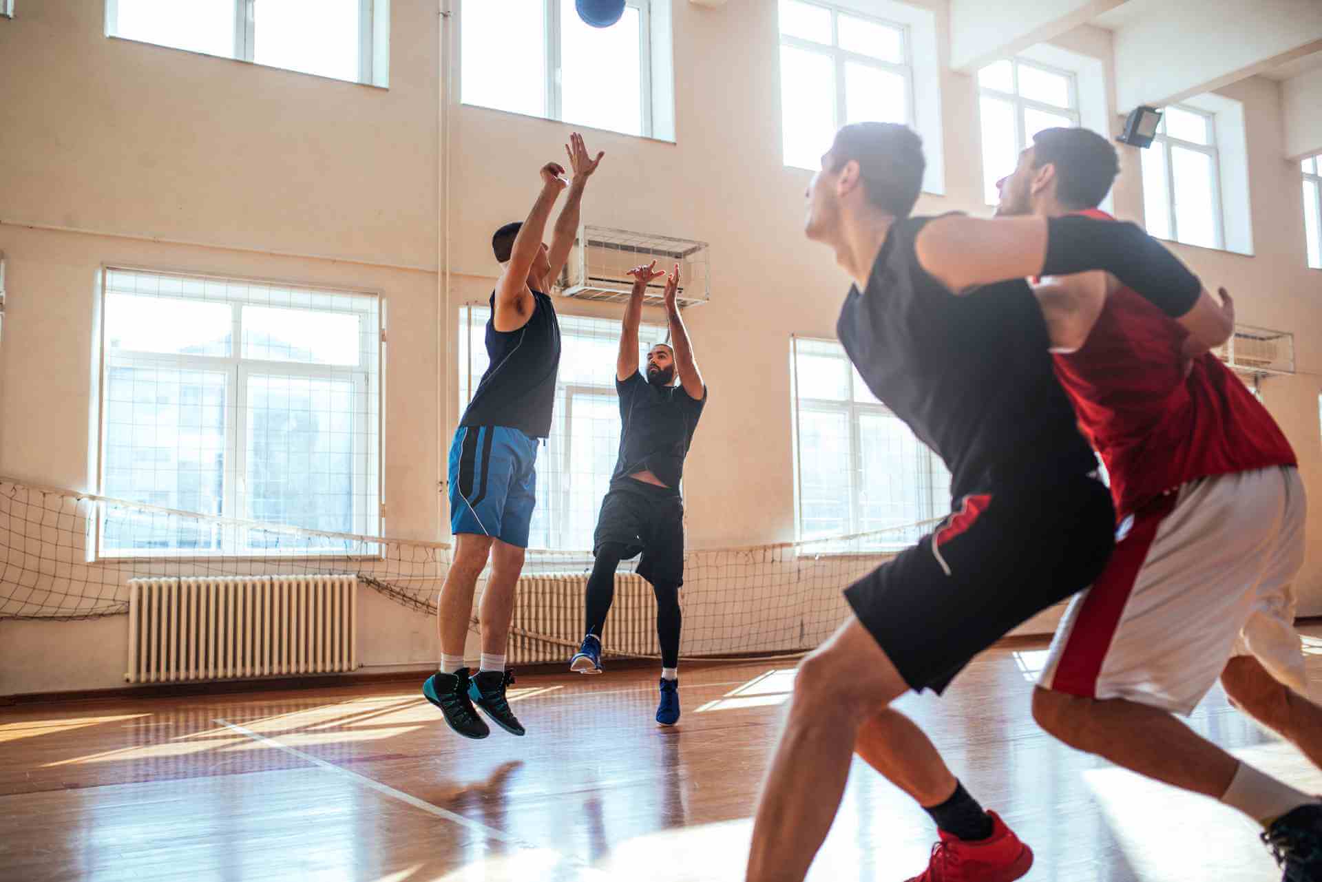 Four young men play basketball together on an indoor court