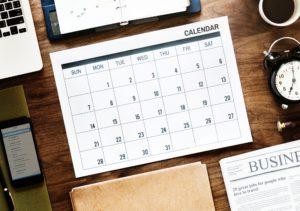 Blank paper appointment calendar laid out on a wood desk 