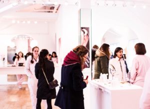 Shopping woman in a white store with phone in hand, looking at a display