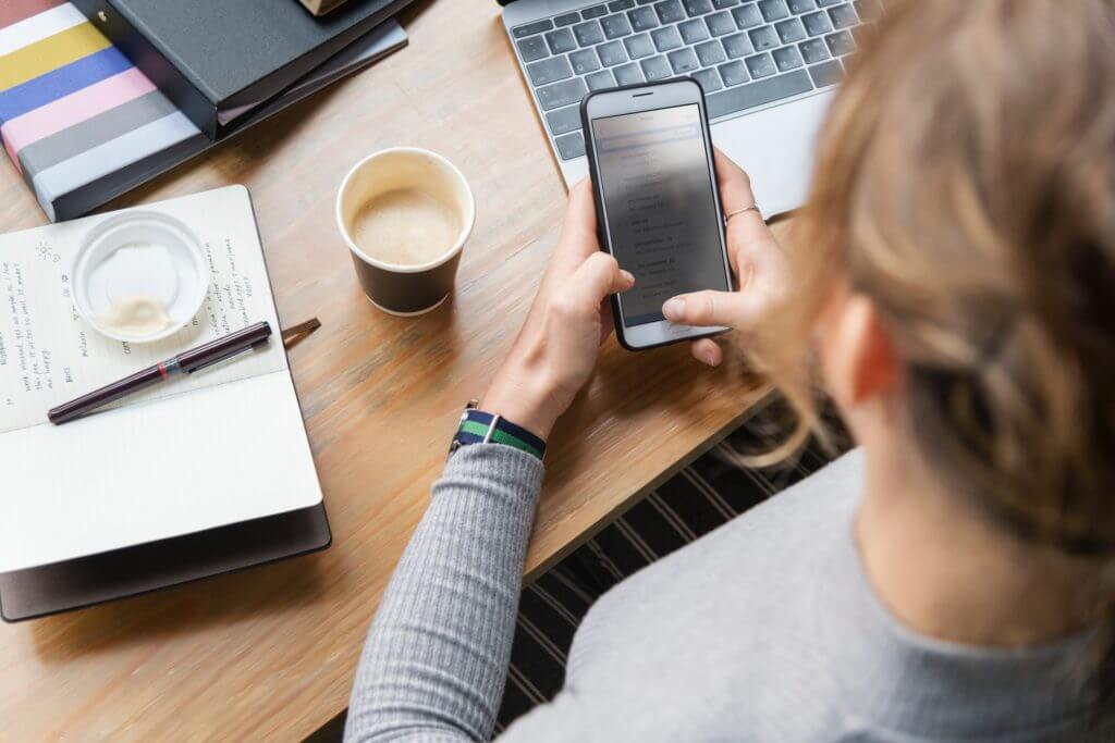 Businesswoman holding phone and replying to customer messages through business text messaging app