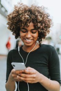 Woman with earbuds checking phone.