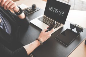 Business person's desk with phone, computer, and tablet.