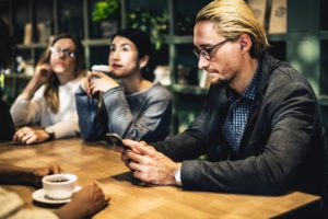 Man at coffee shop checking business SMS.