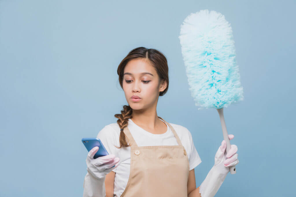 Woman looking at phone while house cleaning