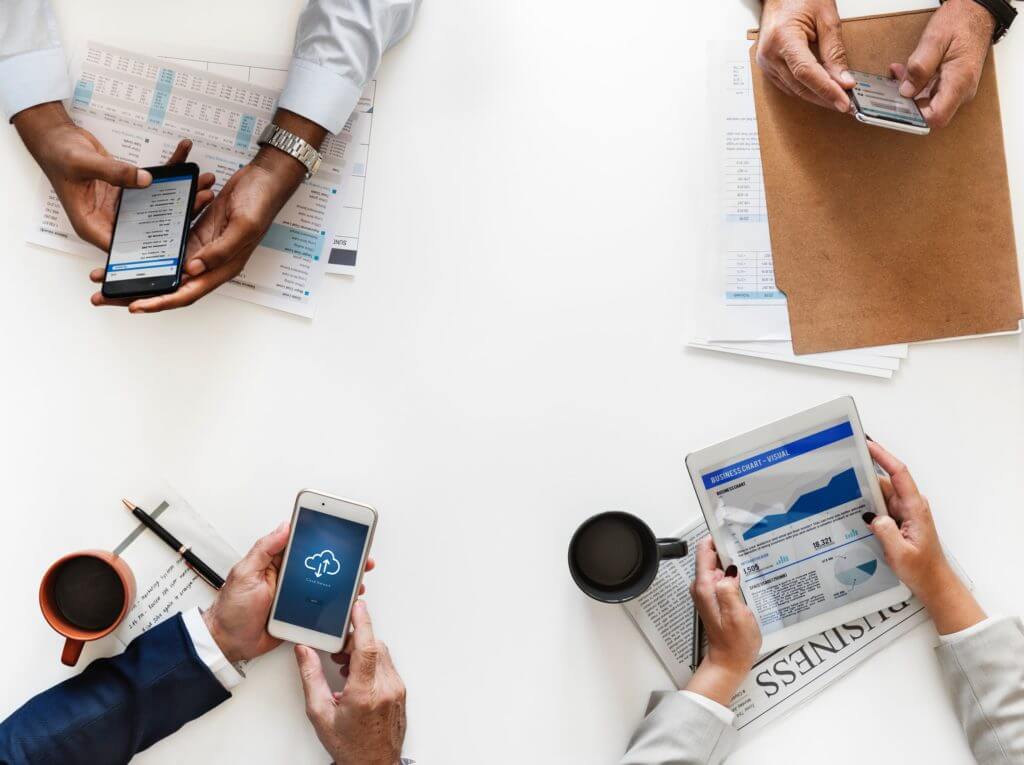 Business people using phones at table.