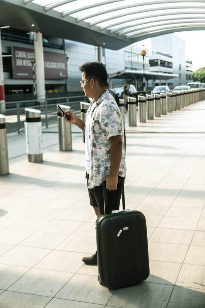 Hotel guest with luggage and checking phone.