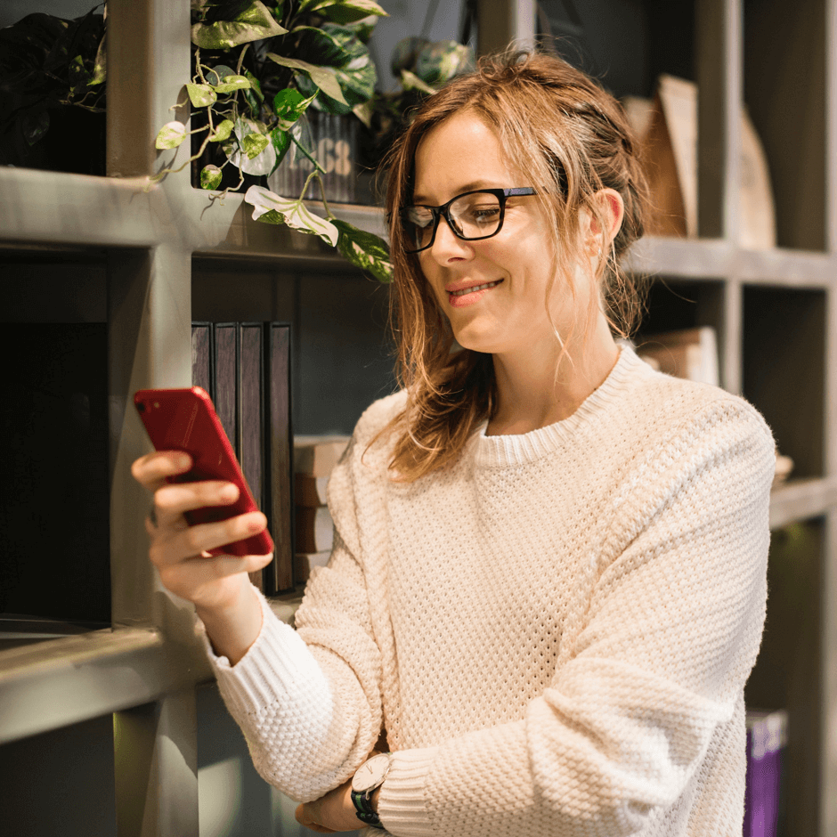 Businesswoman in office smiling at business SMS app on her phone