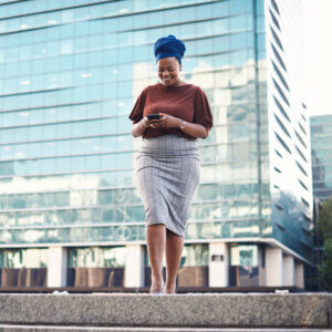 Businesswoman texting in front of a glass office building