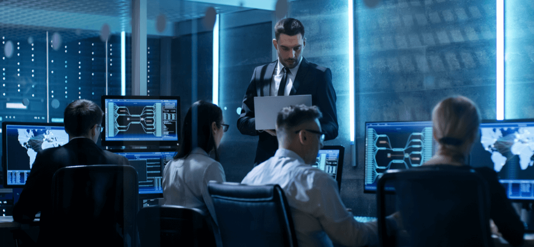 Blue-lit office with five serious-looking team members on computers; all working on SMS security and SMS compliance