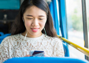 Student on bus reading a text sent through SMS for colleges