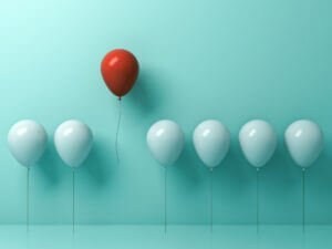 A red ballon amongst blue balloons shows how business texting services help you stand apart