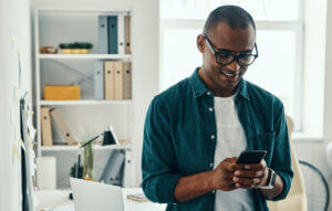 Man at home smiling at phone as he reads SMS customer engagement content