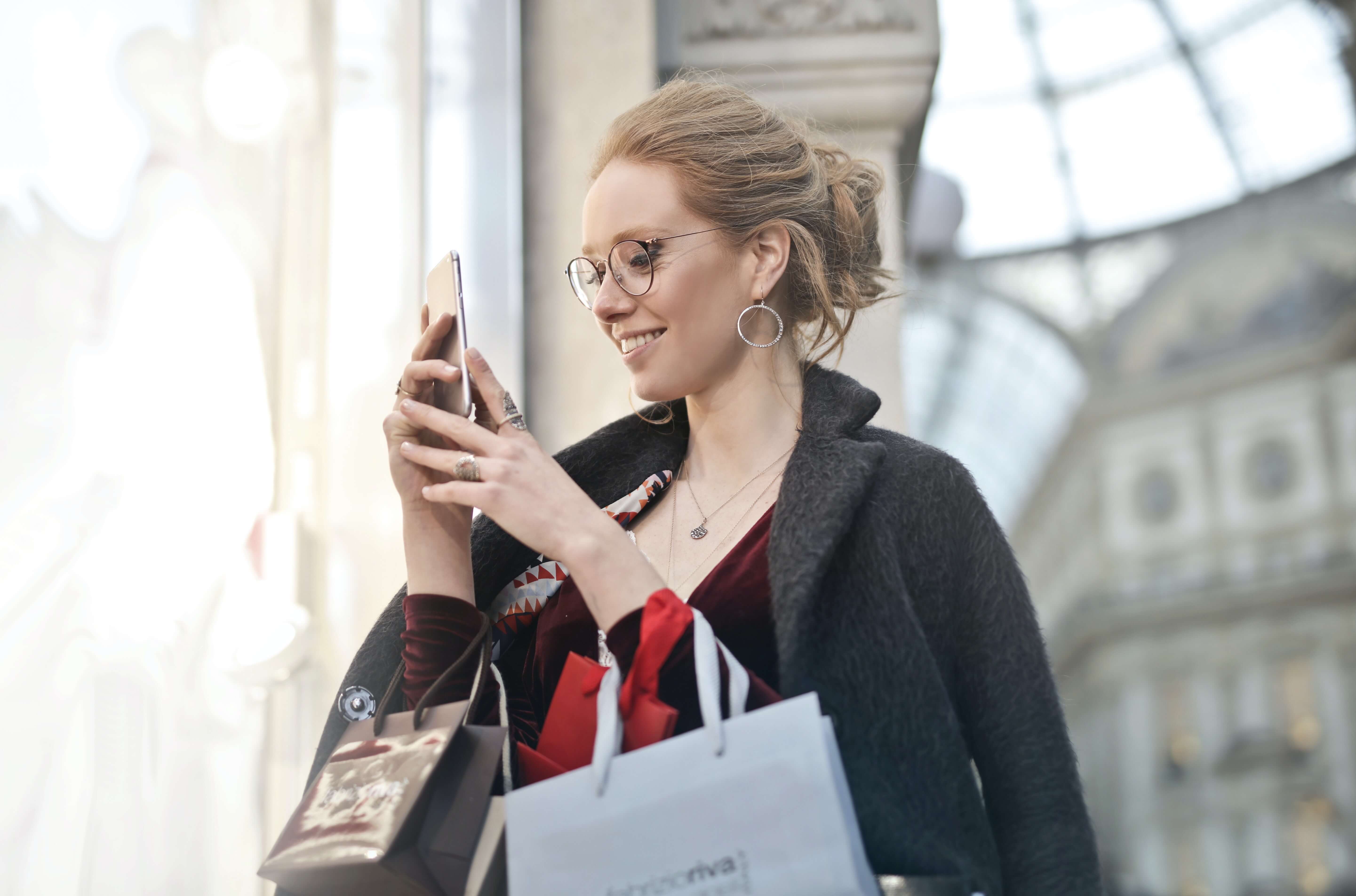 Redheaded shopper smiling at retail SMS message with helpful marketing content