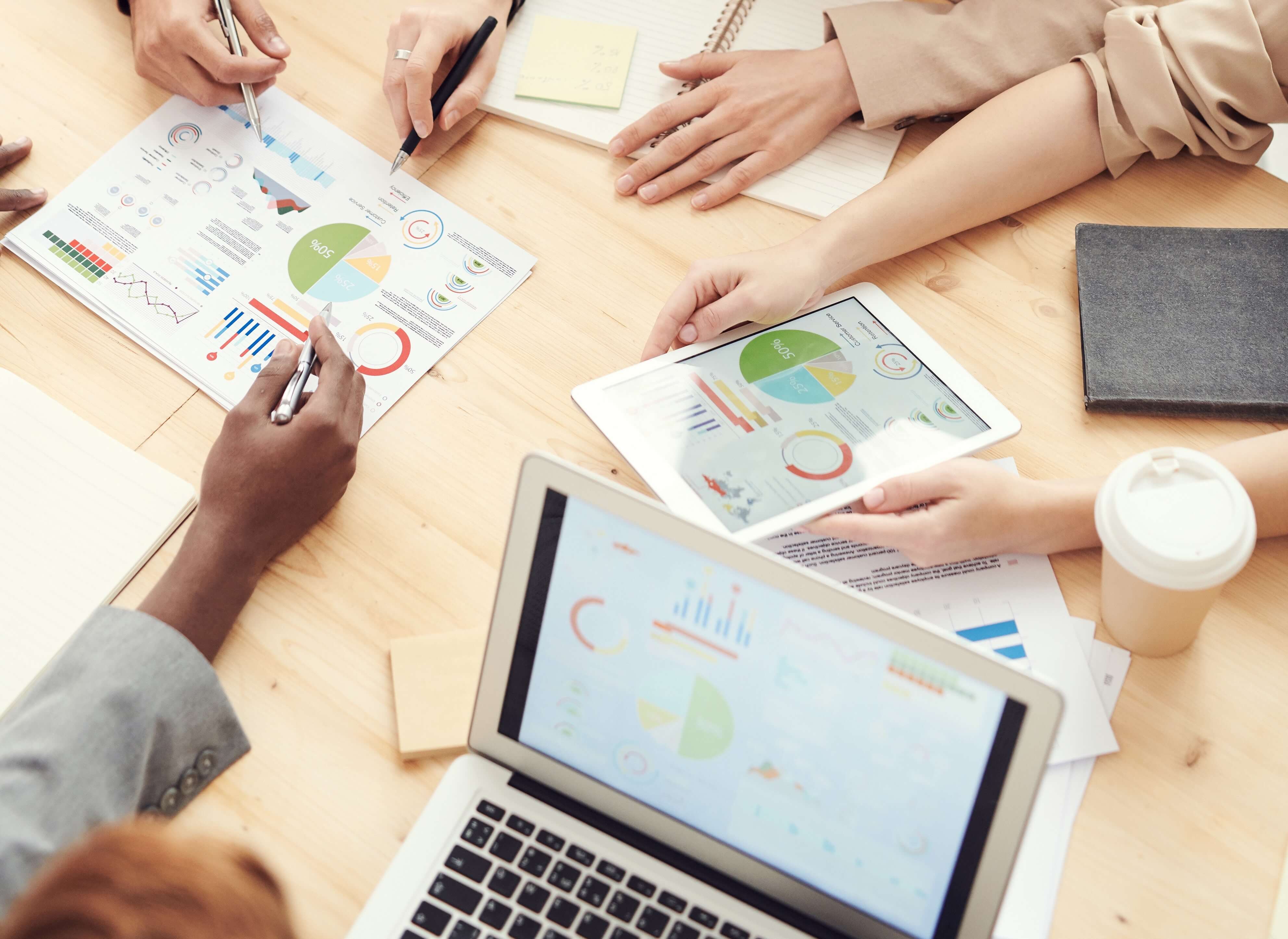 Three firm team members reviewing printed finance SMS reports on desk