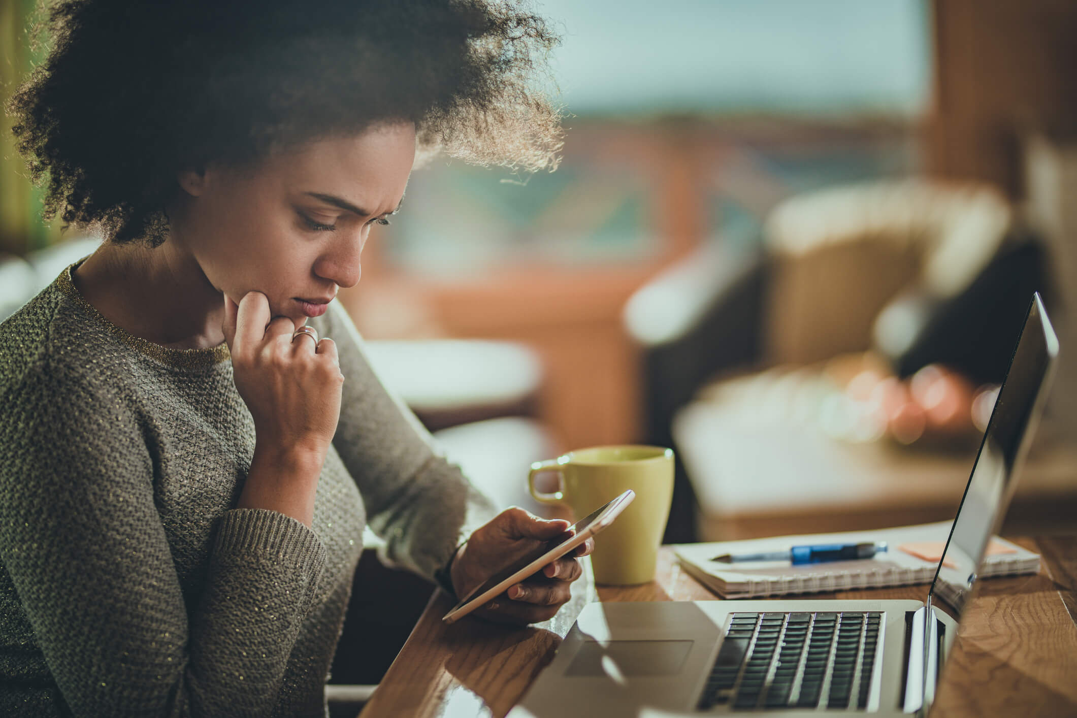 Young woman texting near her computer