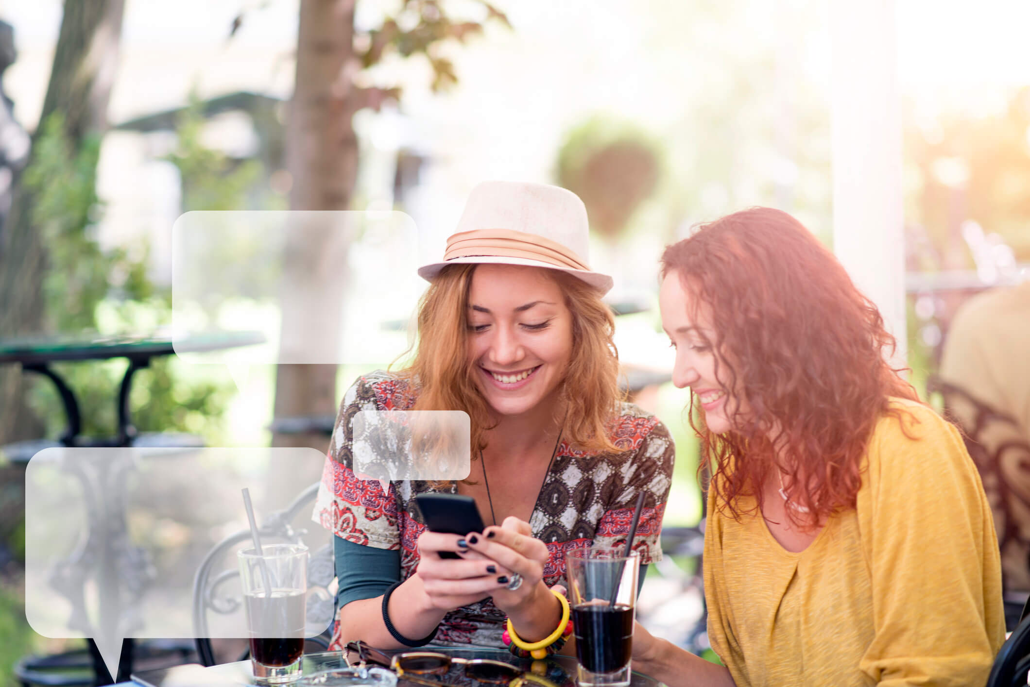 Two happy friends texting in a cafe