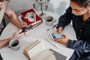 Two team members at circular table on their smartphones, using conversational customer engagement to chat with customers