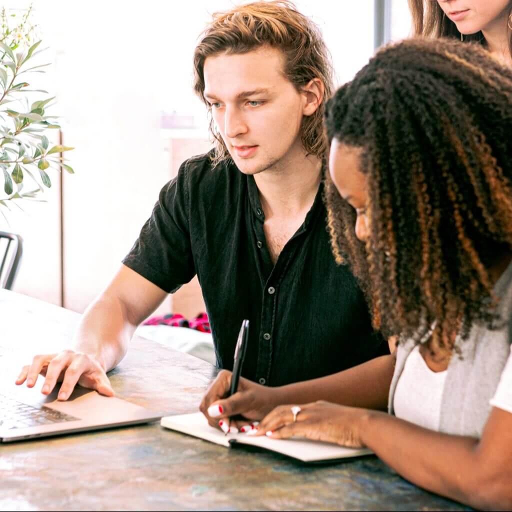 Two team members in front of laptop working together to create a conversational marketing CTA for a text message