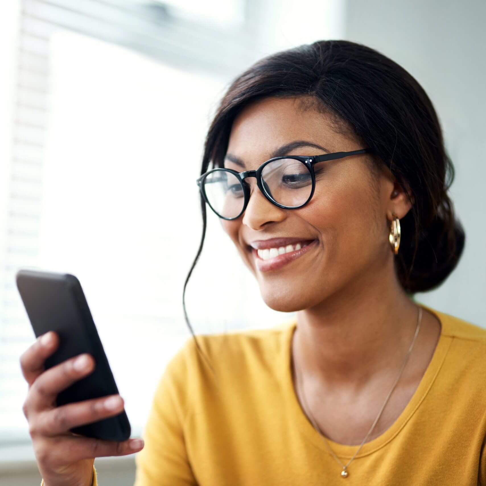 Woman smiling and using business text messaging while working remotely