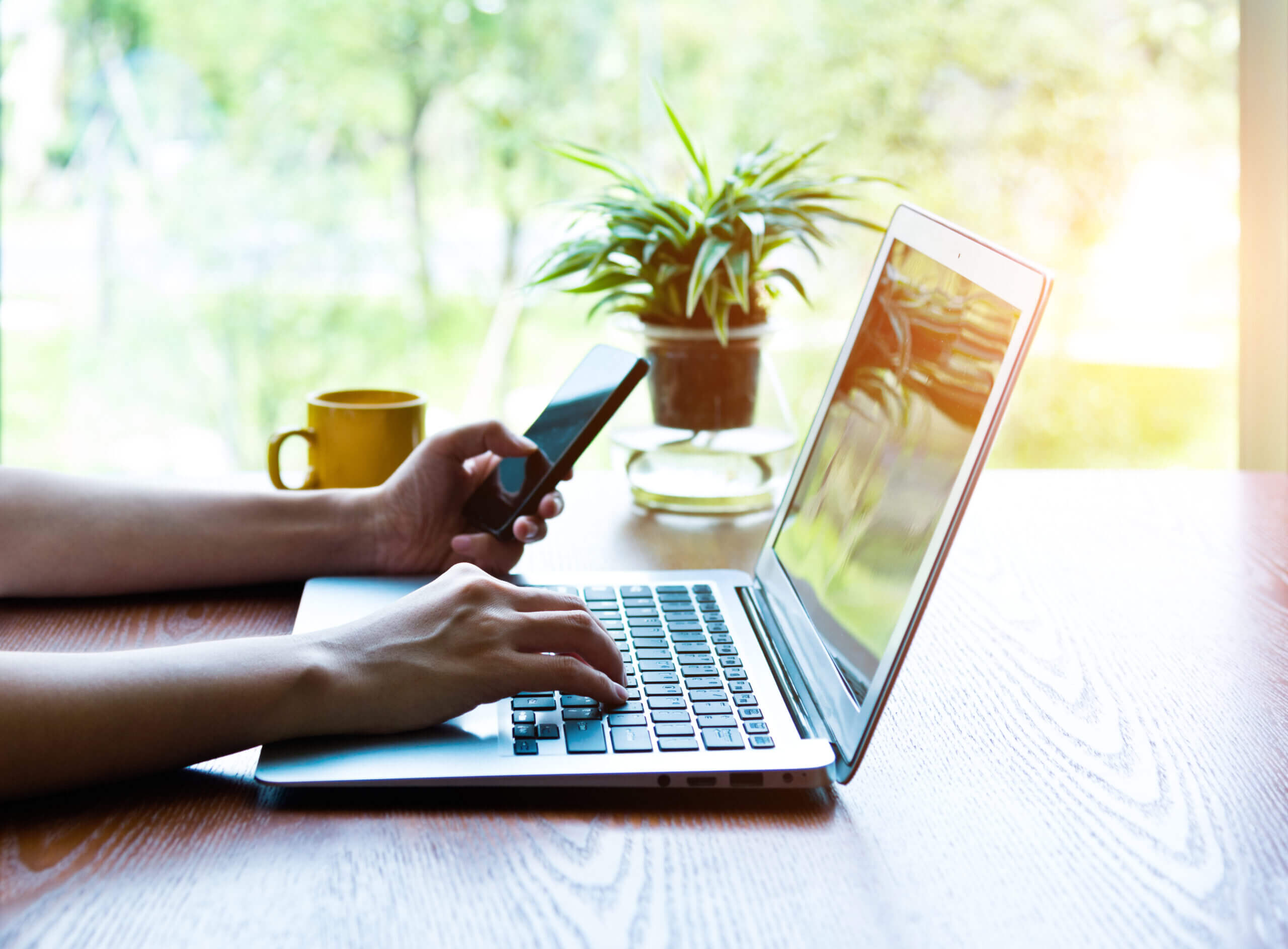 Hands at a keyboard with phone using conversational customer engagement.