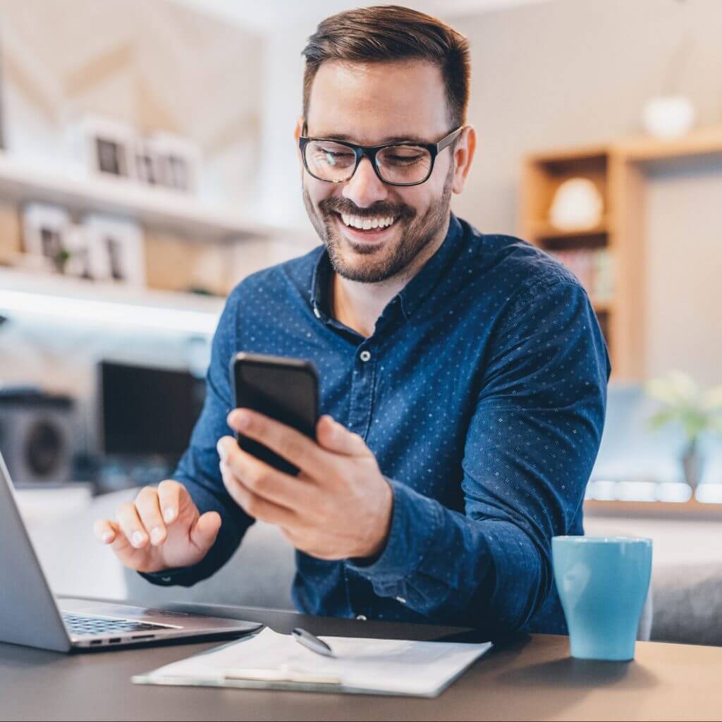 Man working on laptop and texting.