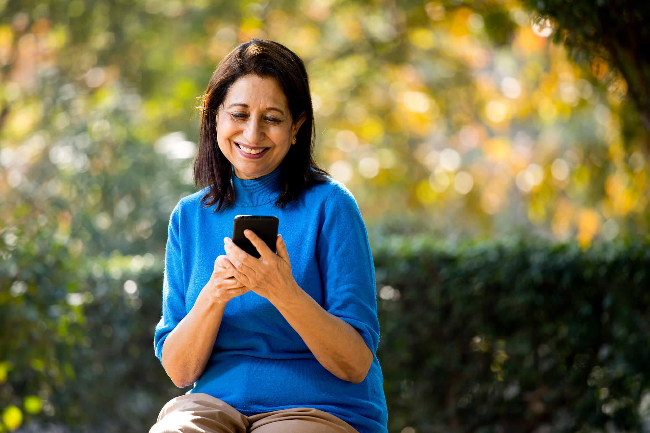 Woman in yard texting and smiling