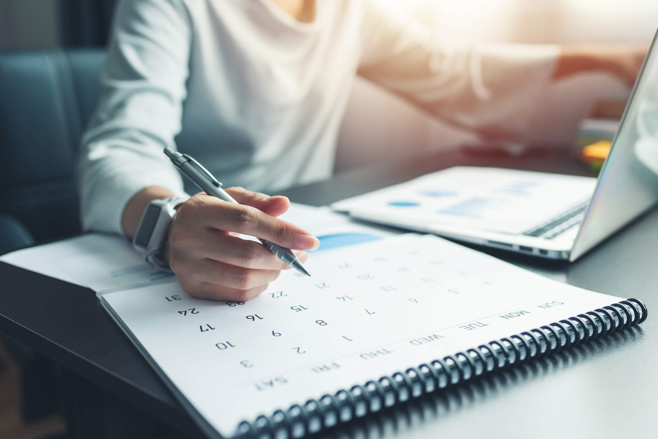 Person's hands writing on calendar