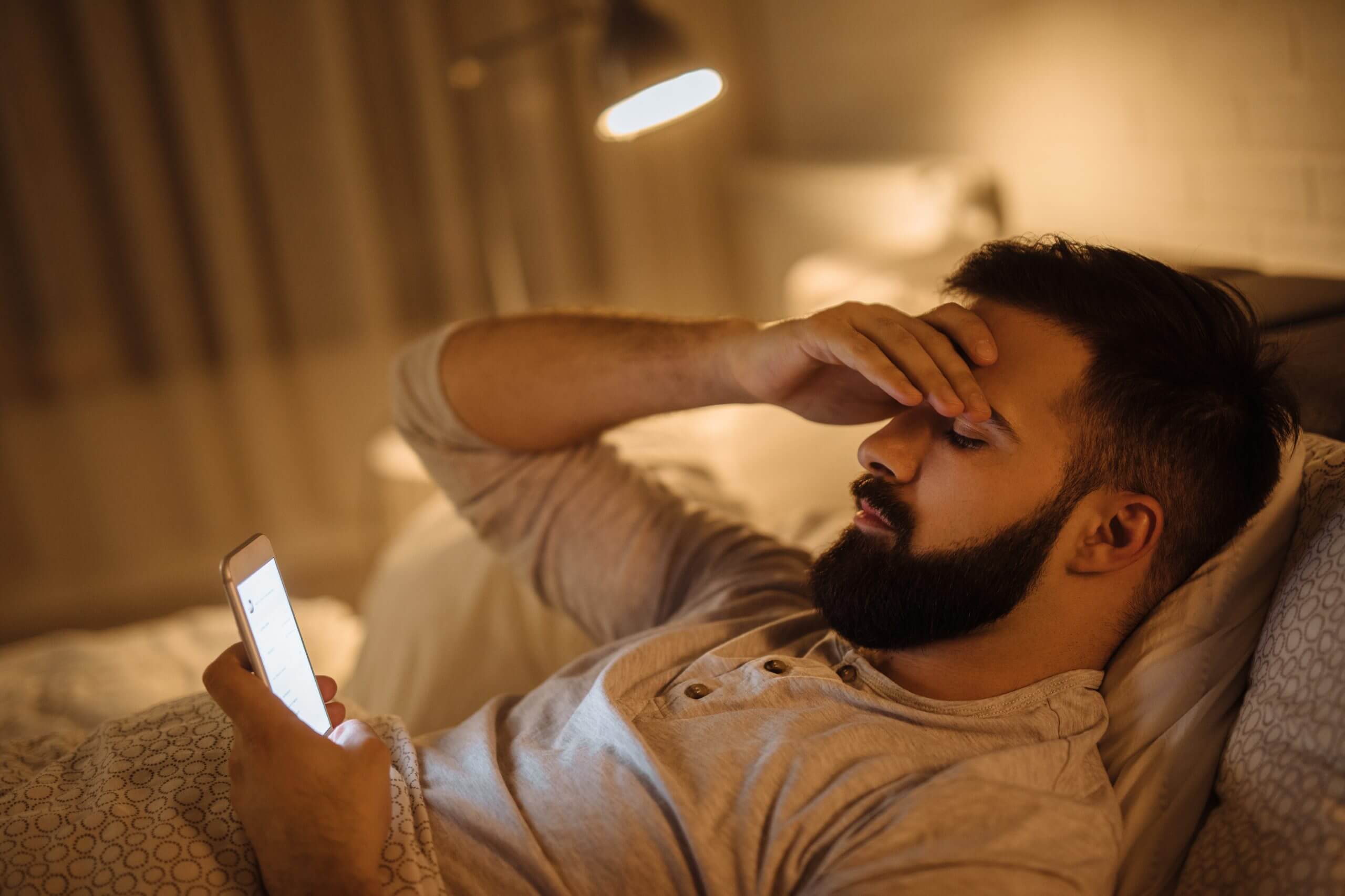 Man lying in bed using personal phone for business text messaging