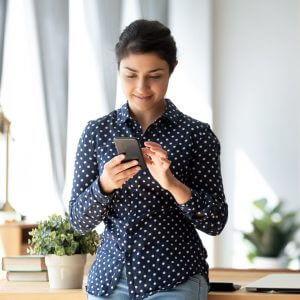 Woman leaning against desk and texting.