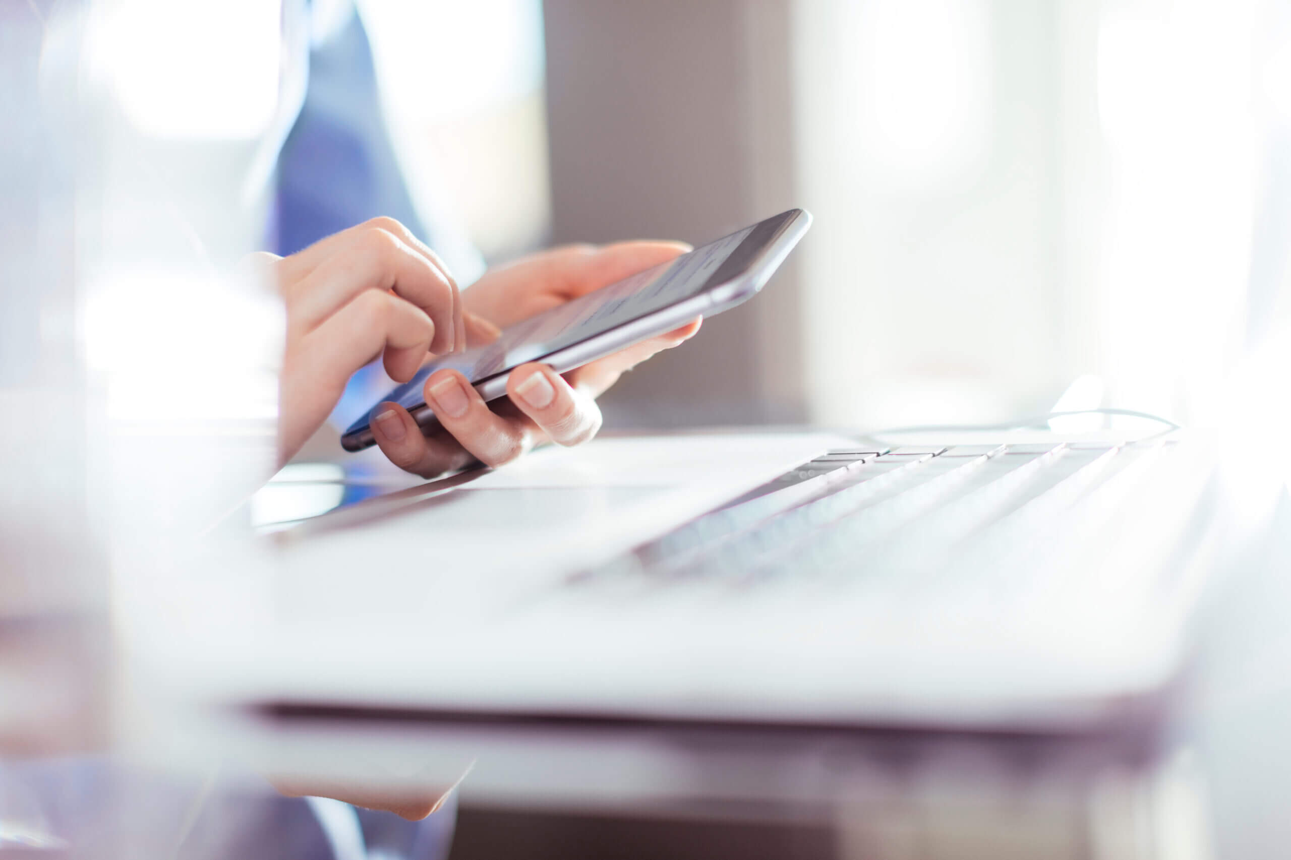 Businesswoman using smartphone and laptop.