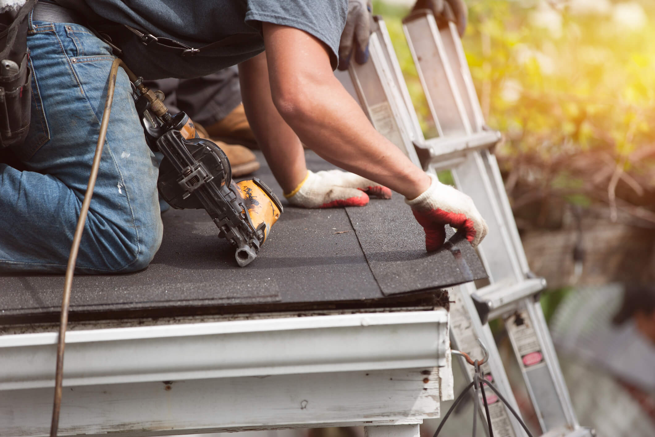 Roofers laying roof shingles on house