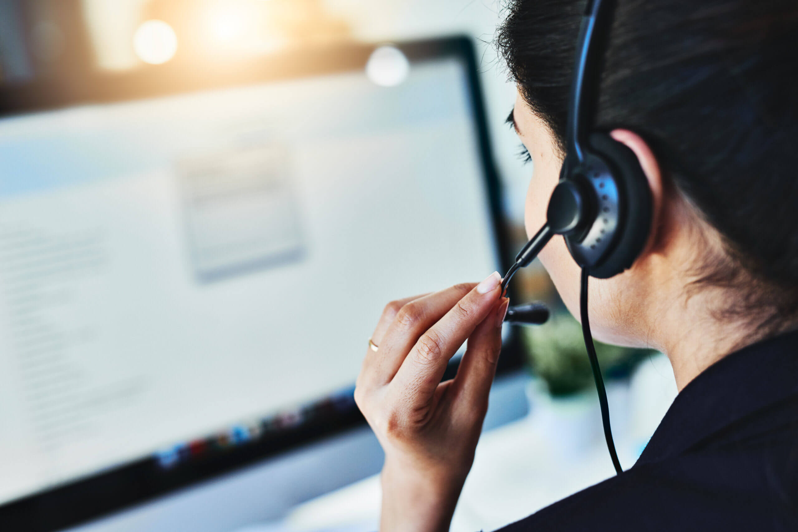 Woman talking into headset working at computer.