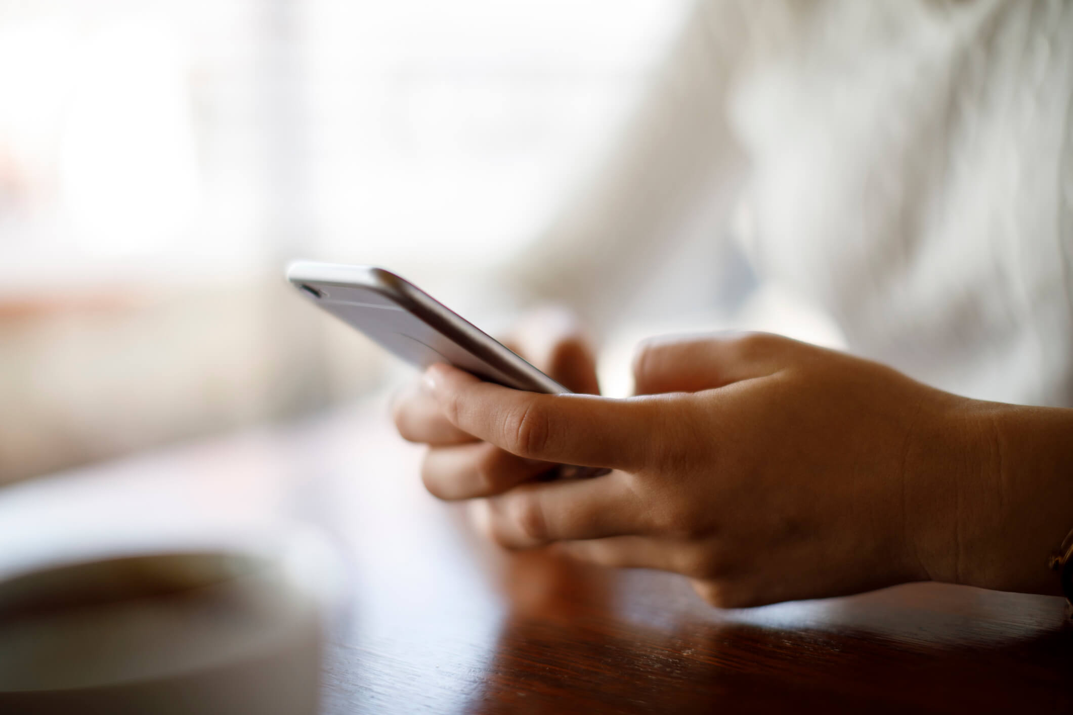 Hands texting on wooden tabletop