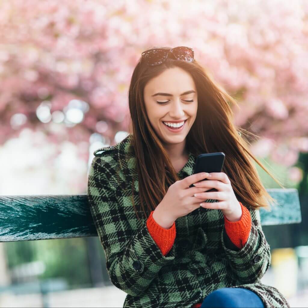 Texting with SMS templates next to blossoming tree.