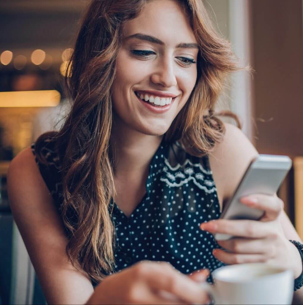 Woman smiling into phone while texting with conversational customer engagement