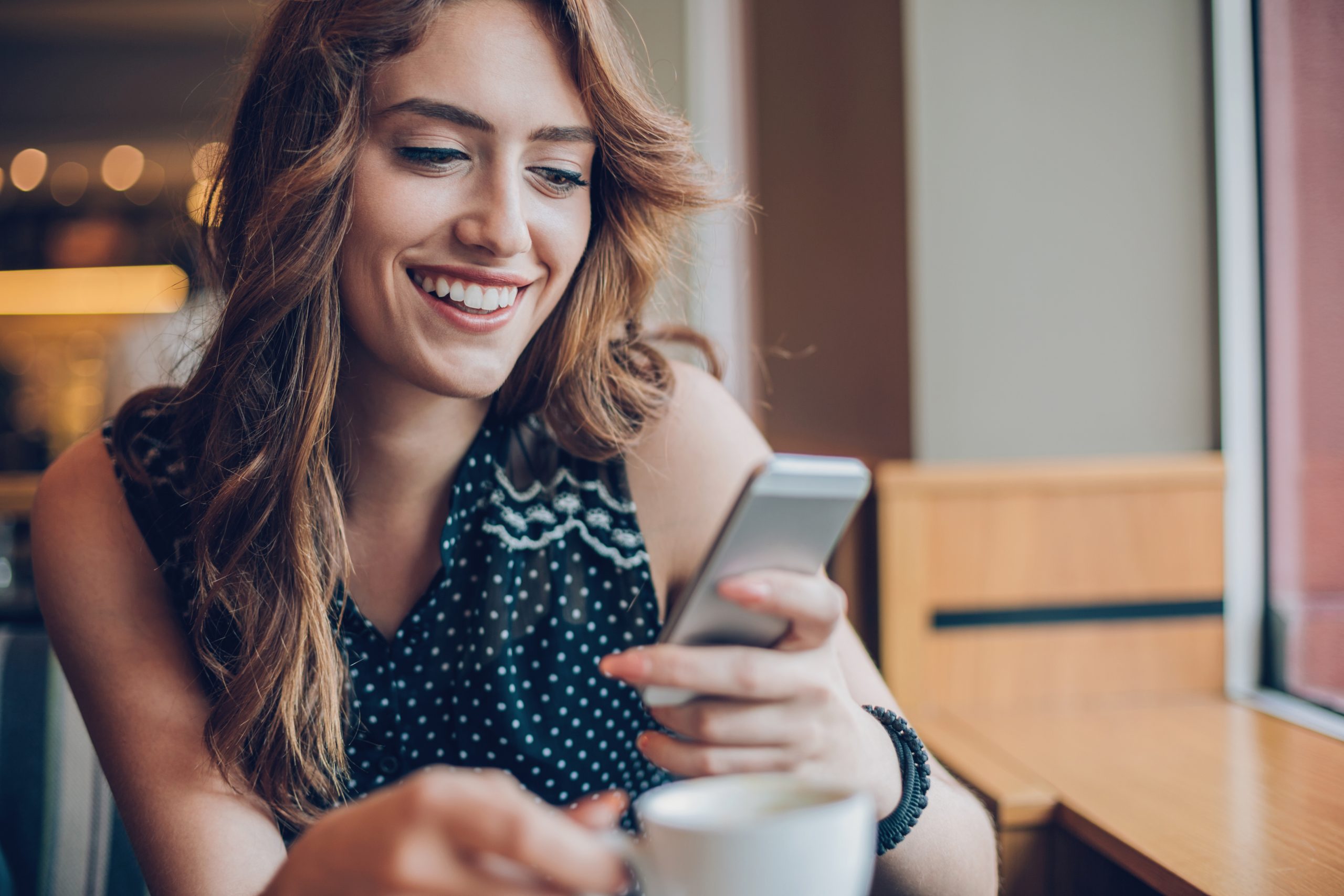 Woman smiling into phone while texting with conversational customer engagement