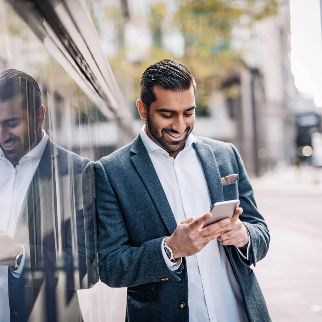 Salesperson learning against a wall texting a follow up SMS