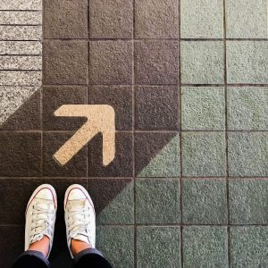 Shoes on pavement next to an arrow to signify starting with Conversational Customer Engagement