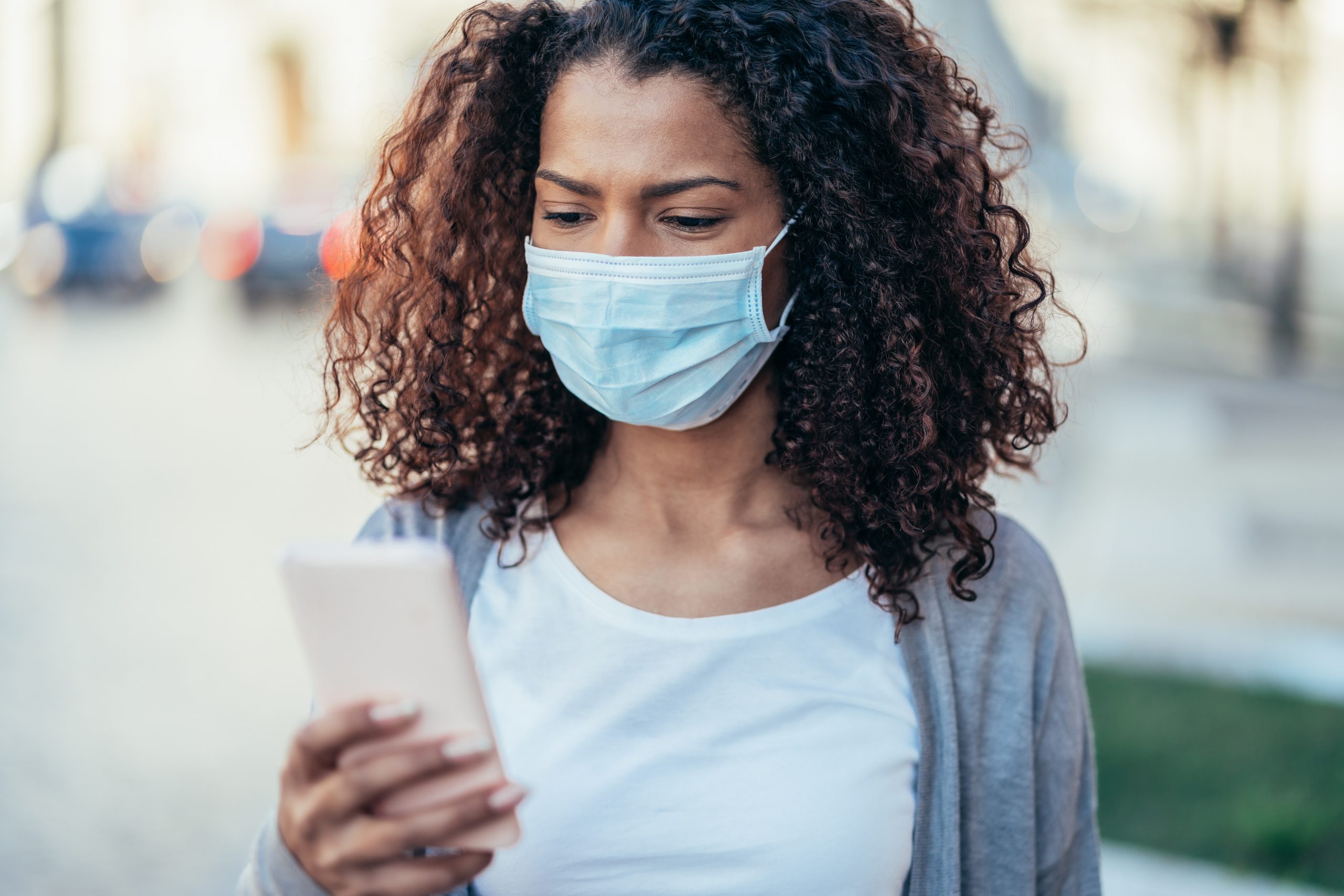 Woman wearing face mask and texting to illustrate how stores can use texting to help customer covid concerns