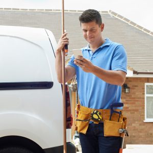 Plumber in front of van using text messaging for home services