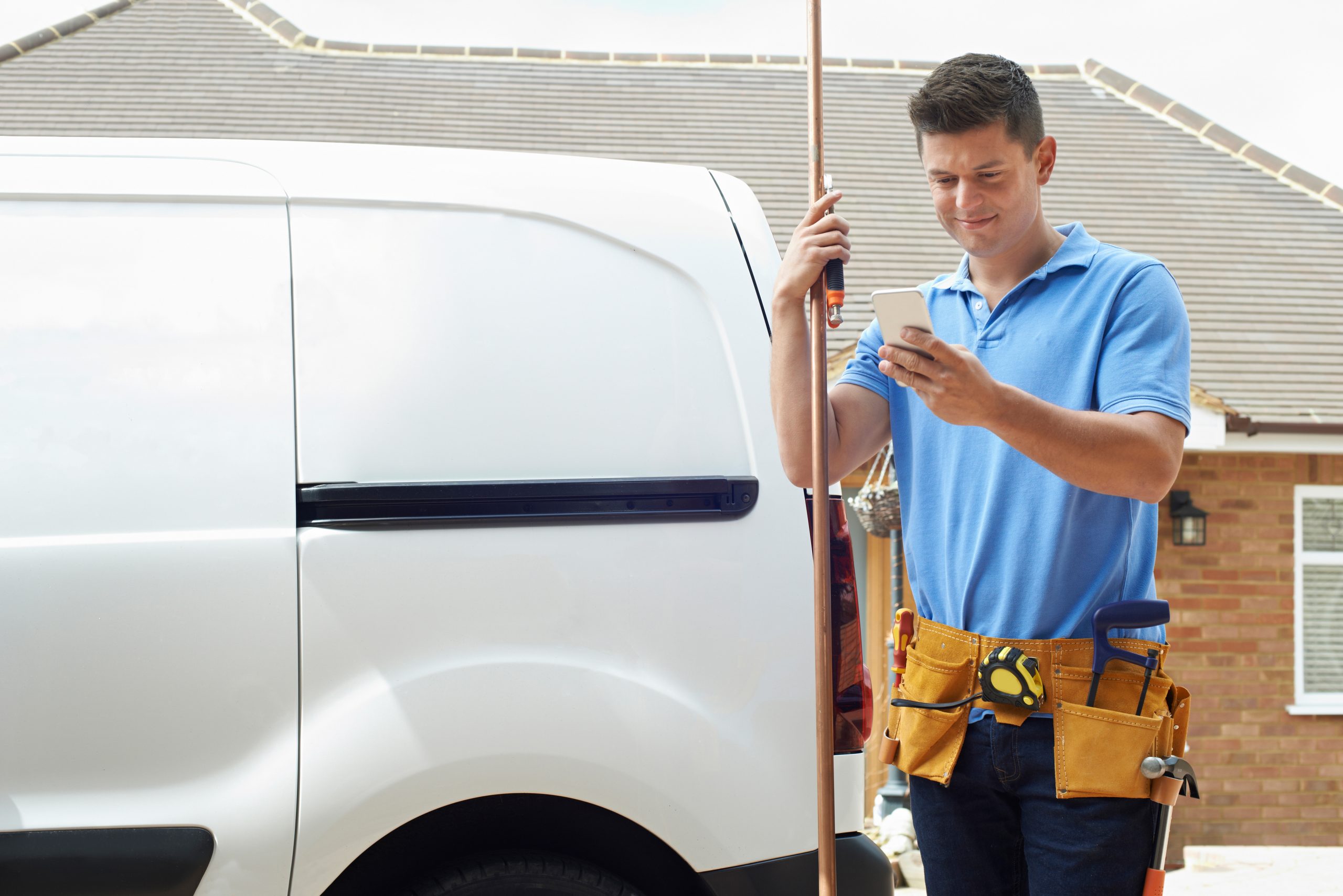Home repair worker in front of van using text messaging for home services