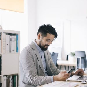 Businessman at computer and on phone using Conversational Customer Engagement for subscription companies