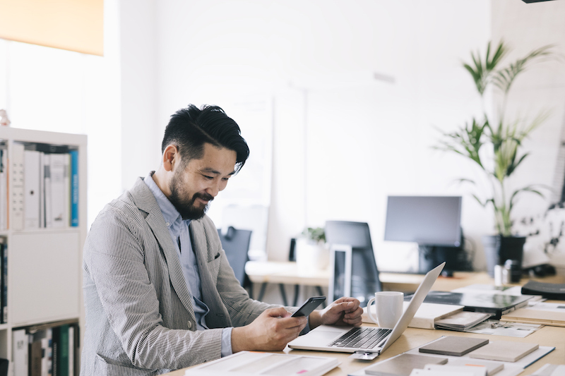 Businessman at computer and on phone using Conversational Customer Engagement for subscription companies