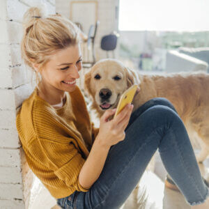 Woman texting happily with her golden retriever next to her, showing the impact of conversational marketing