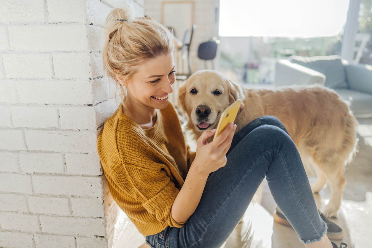 Woman texting happily with her golden retriever next to her, showing the impact of conversational marketing