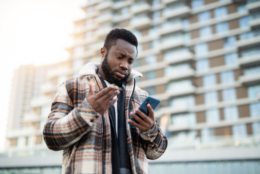 Man texting and walking while looking frustrated at phone