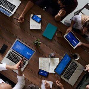 New tech stack examples demonstrated by professionals working around a table with phones and laptops