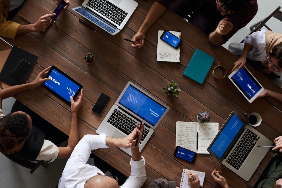 New tech stack examples demonstrated by professionals working around a table with phones and laptops