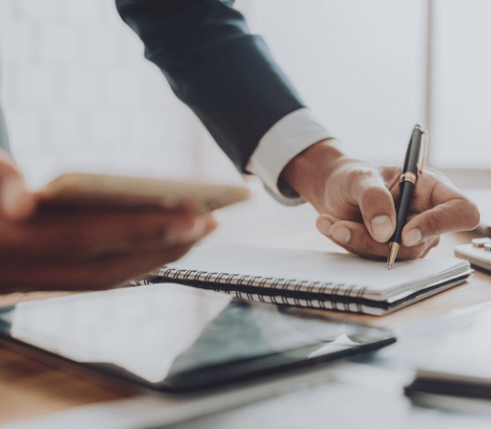 Business person's hands checking off a checklist while texting on phone